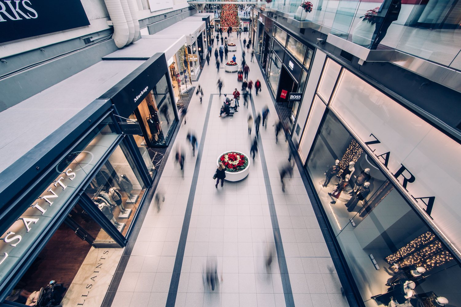 A busy shopping mall interior with shoppers browsing across multiple levels
